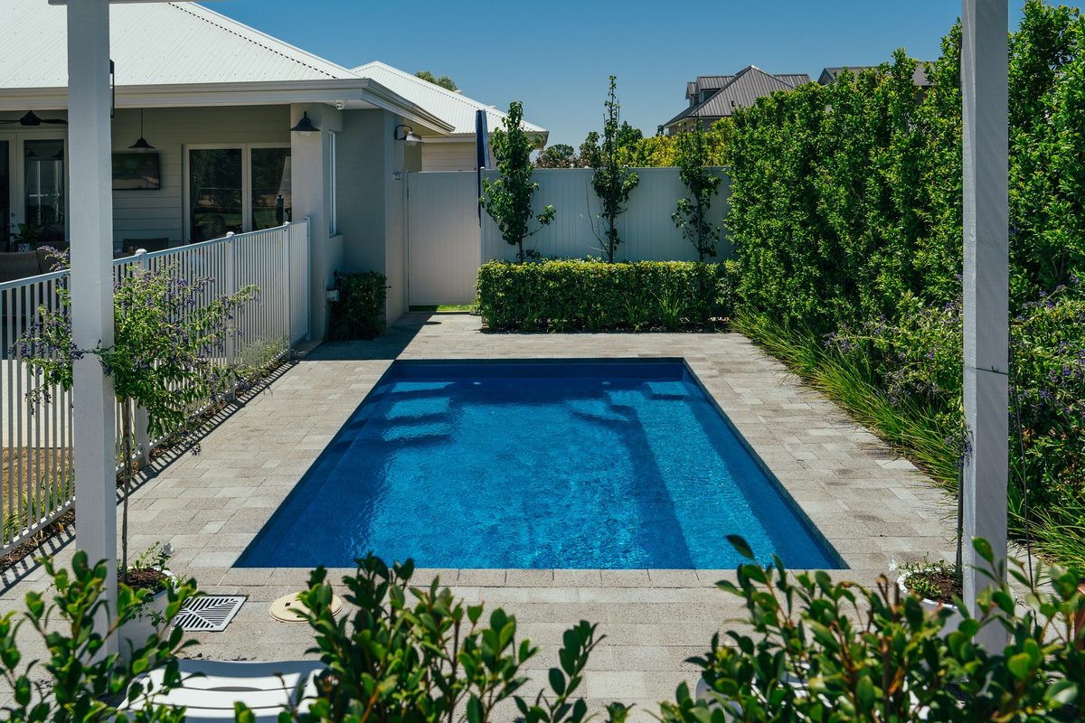 Fibreglass pool framed by a garden and white fence, from the Wetlife Pool Co gallery